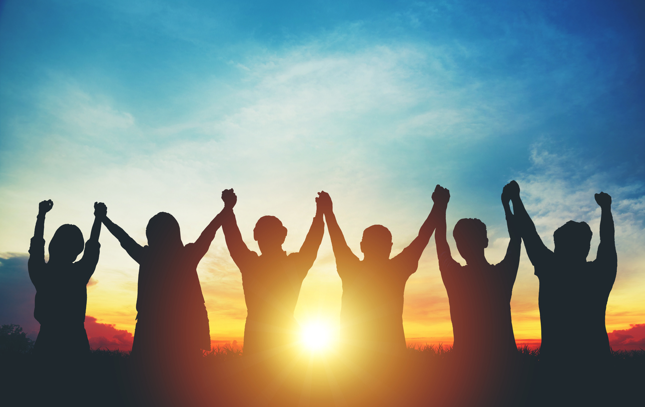 Silhouette of group business team making high hands over head in sunset sky